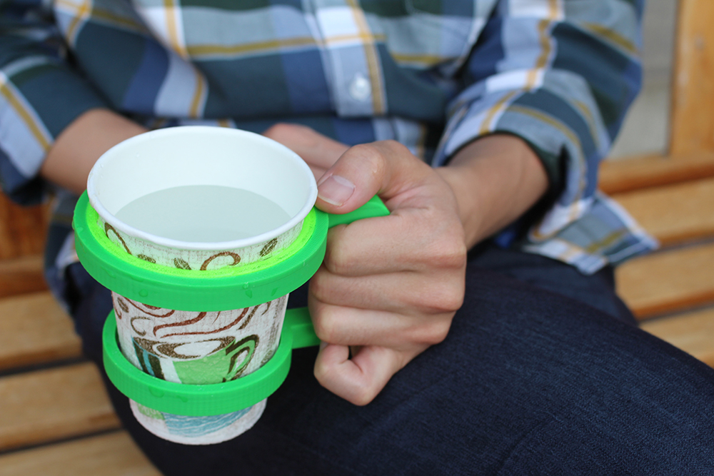 A user holding a 3D-printed cup holder augmented with a flexible ring generated using our flexible buffers technique.